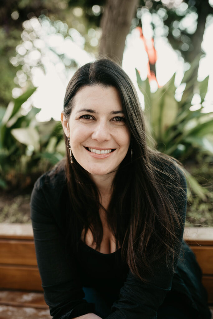 Woman smiling among green plants – natural outdoor brand portrait