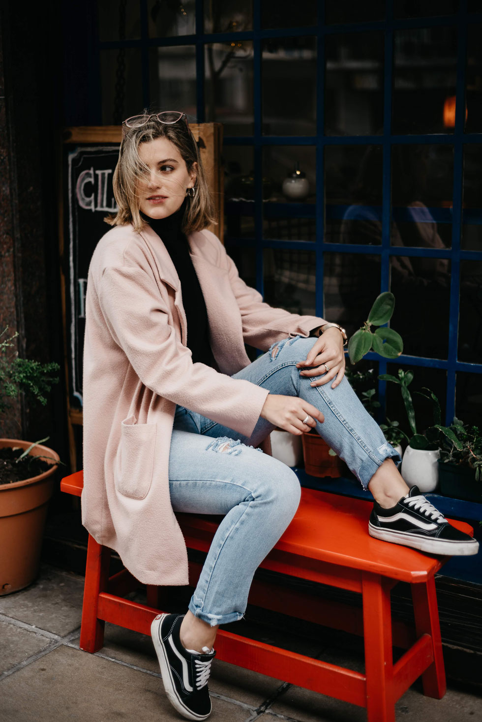 Woman in a pink coat sitting on a red bench, natural portrait by Pau Granillo, documentary photographer in Haarlem