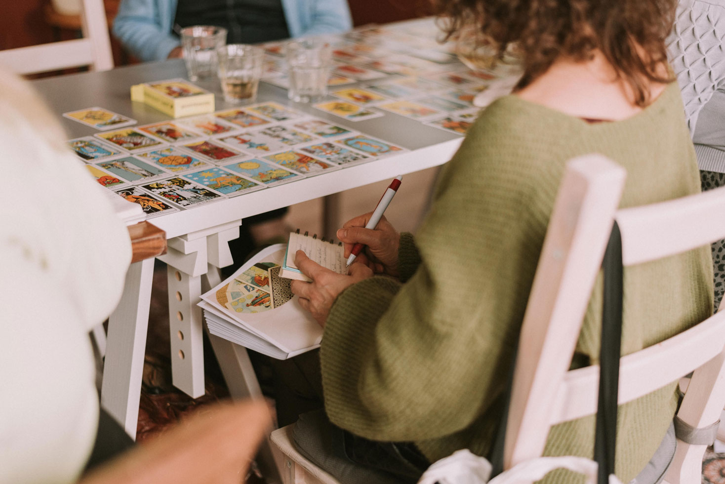 Workshop participant taking notes next to a table covered with tarot cards