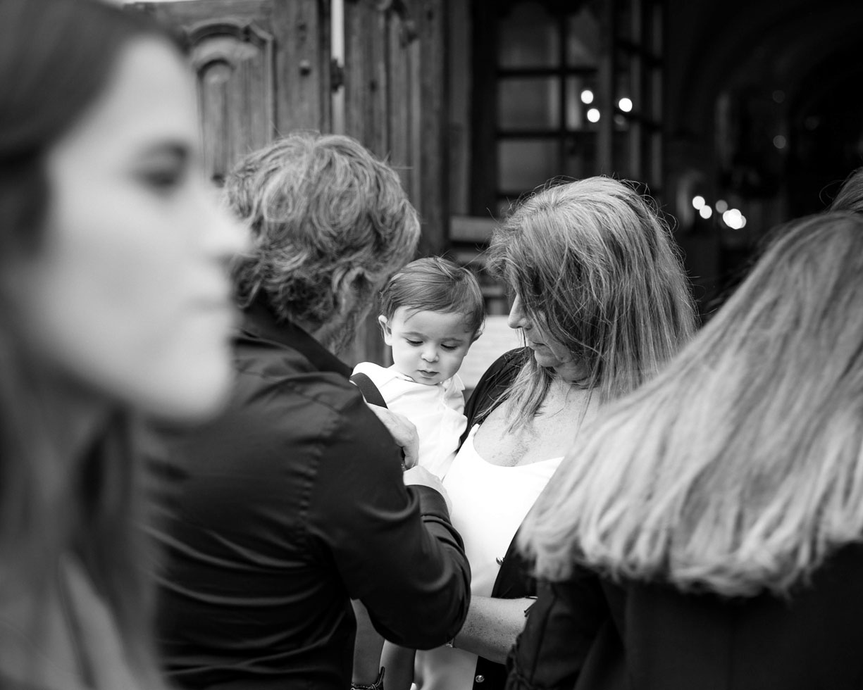 Black and white photo of a baby held by his family at a christening