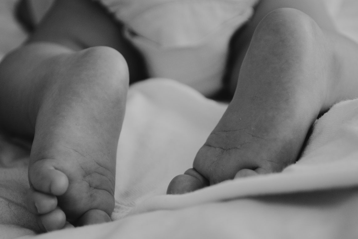 Close-up of tiny baby feet on a white blanket – newborn photographer Haarlem