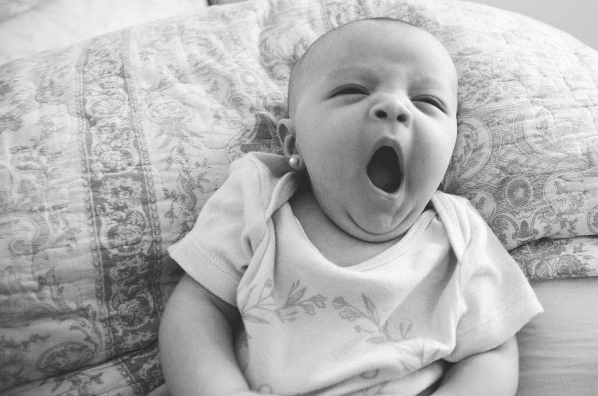 Baby yawning against a patterned pillow – relaxed, unposed newborn photos in Haarlem