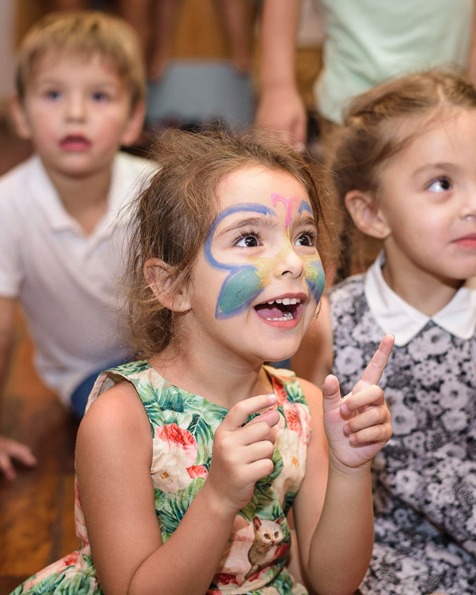 Girl with a unicorn headband and face paint looking up during a family celebration