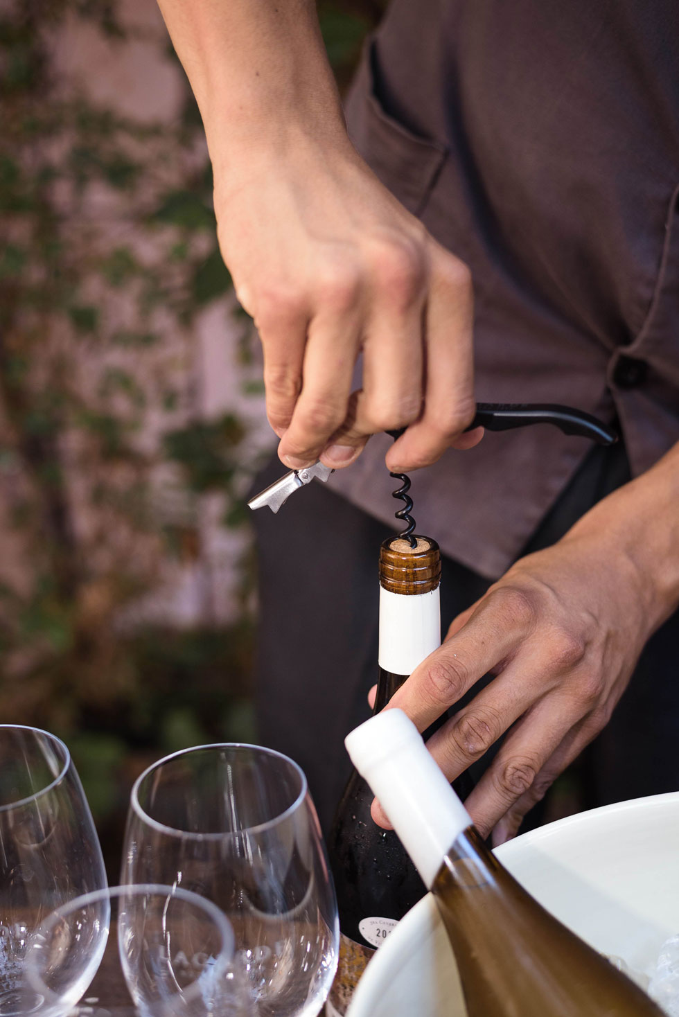 Waiter opening a bottle of white wine next to empty glasses at a corporate event