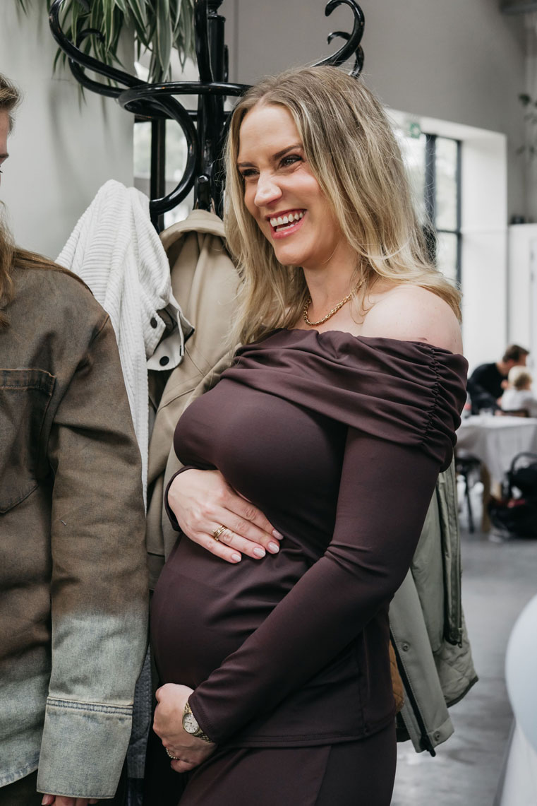 Pregnant woman laughing with her hands on her bump next to a friend at her baby shower
