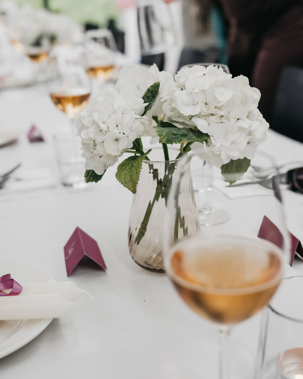 White hydrangeas and glasses of rosé on a long table set for a baby shower