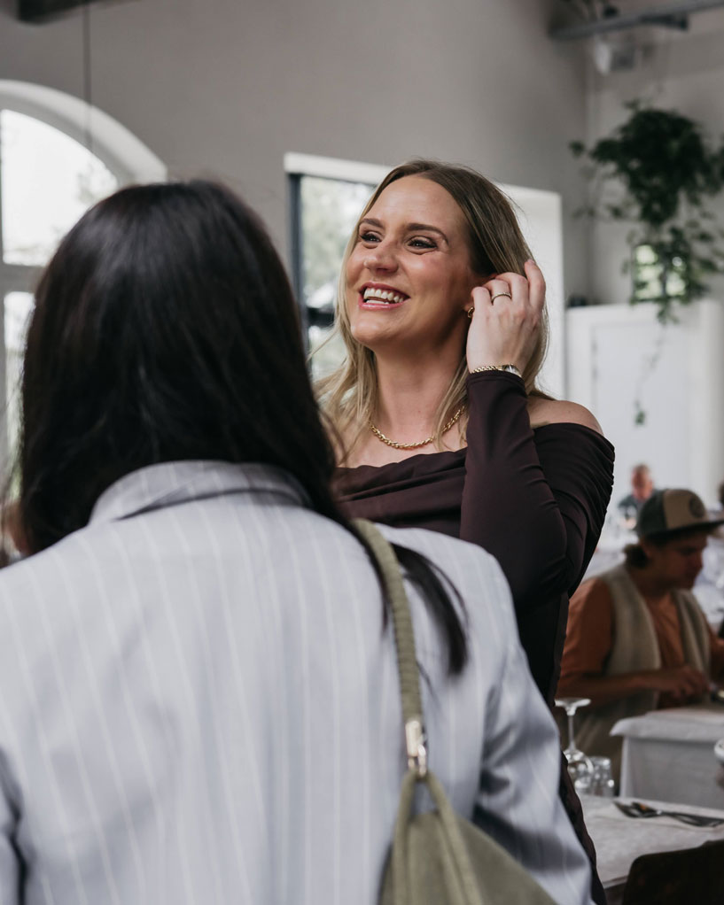 Mum-to-be laughing and touching her hair while talking to friends