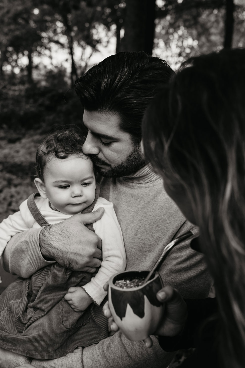 Father kissing his baby’s head while the mother holds a mate during a family photoshoot in Amsterdam