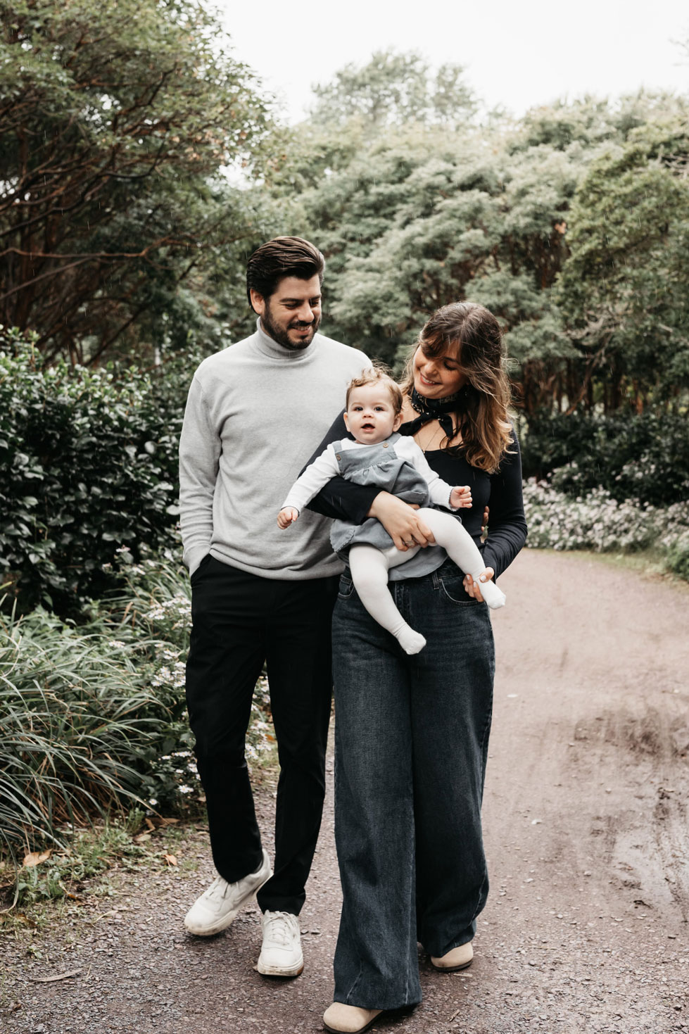 Family walking along a green path in Westerpark, Amsterdam, with their baby daughter