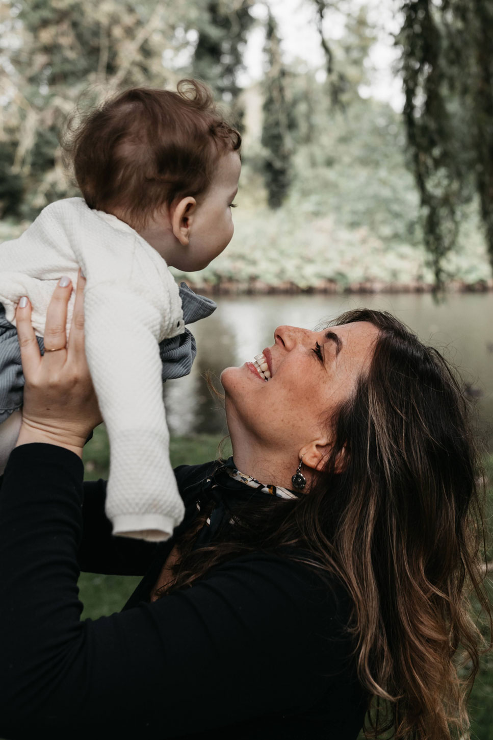 Mother lifting her baby up by the pond in Westerpark, Amsterdam, both smiling